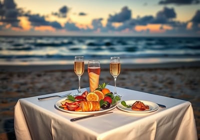 A beautifully set table for two on the beach, adorned with luxurious food and glasses of champagne, 