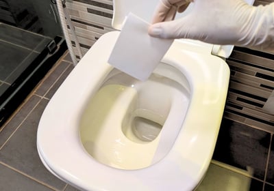 eco-friendly toilet cleaner sheet being dropped in the toilet bowl