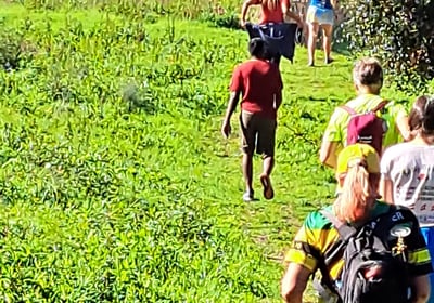 people climbing a grassy trail