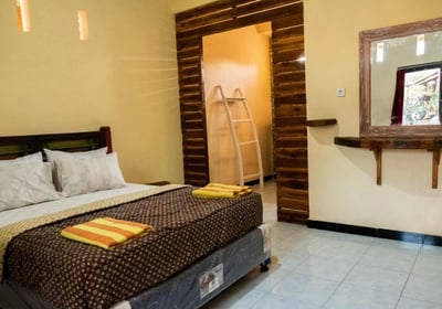 a bedroom with a bed and a mirror our happy and confortable room at sunrise lodge and lounge lovina 