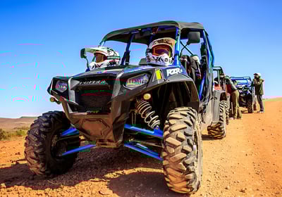 a group of people riding a quad bike buggy on a dirt road in the desert