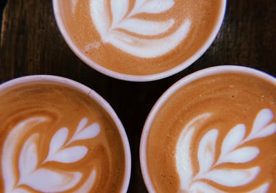 three cups of coffee with a leaf design on the bottom