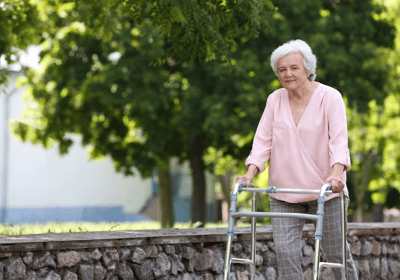 a woman with a walker frame walking outside - The London Physio