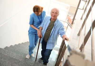 An elderly patient practising walking up stairs with The London Physio