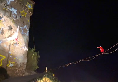 Le pere Noel marche en equilibre sur un fil en direction de mere noel suspendue a un tissu