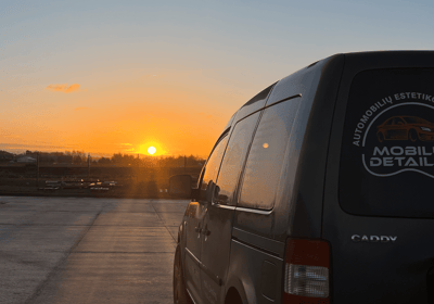 automobilių stovėjimo aikštelėje stovintį furgoną saulei leidžiantis