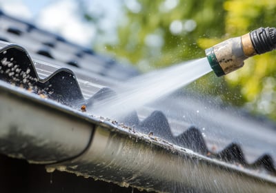 A gutter being cleaned with a pressure washer