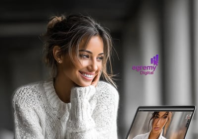 Mujer sonriente con suéter blanco mira laptop en videollamada; branding humano de Egremy Digital.