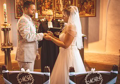 Braut und Bräutigam bei der Trauung in einer Kirche, umgeben von festlicher Dekoration.
