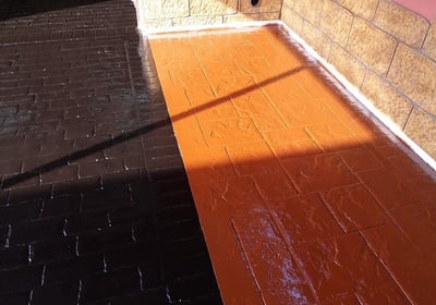 Superficie de hormigón impreso con acabado en resina de dos colores, ideal para crear contraste en áreas exteriores.