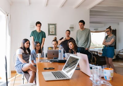 A team gathered around a laptop on a table, attending a virtual meeting.