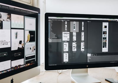 Two monitors displaying mockups for a website design