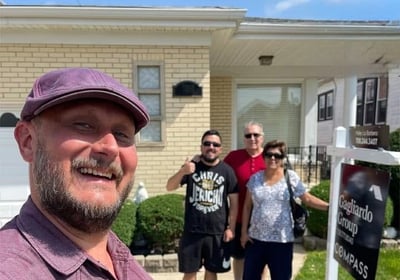 Andy Albright stading in front of a house with happy real estate clients