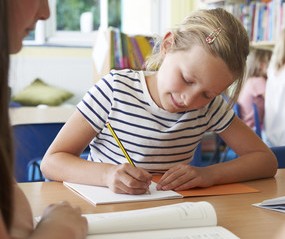 a girl is sitting at a table with a pencil and a pencil