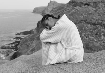 a woman sitting on a rock ledge with her head in her hands. Destination photoshoot 