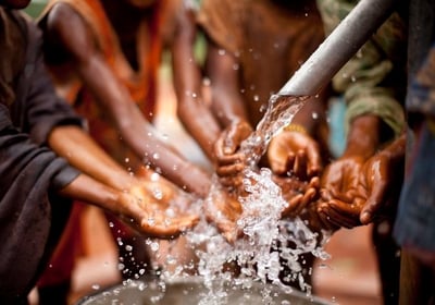 Hands collecting clean water from a community well in rural Africa.