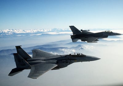 two jets are flying in the sky above the clouds