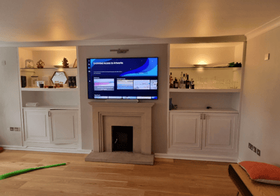 a large screen tv mounted on to a wall above a fireplace. Chelsea