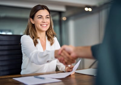a woman in a white shirt and a man in a suit shaking hands