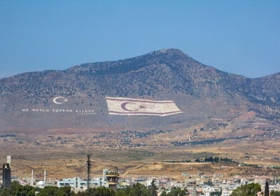north cyprus's flag flying over a mountain range with a flag