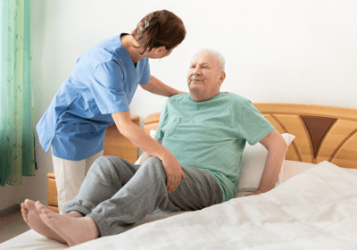 physiotherapy at home for seniors - a physio is helping an elderly man into bed in his home