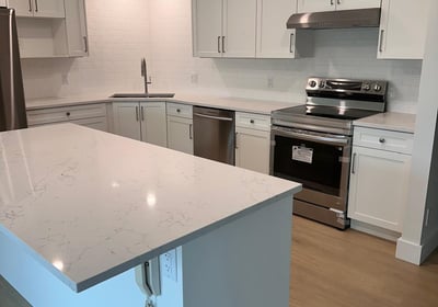 L-shaped kitchen with white shaker cabinets, subway tile backsplash, and quartz island countertop — 