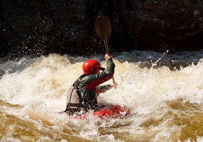 Man-in-red-helmet-paddling-on-water-in-a-boat