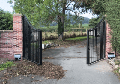 a gated in area with a brick wall and a gated in area with automated gates