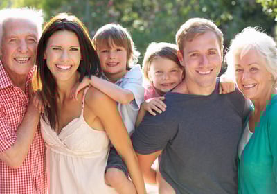 Multigenerational family smiling in front of their home – real estate and mortgage services for all