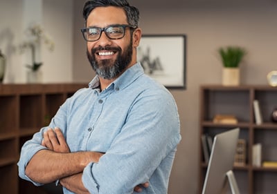 a man with a beard and glasses on his arms crossed and smiling