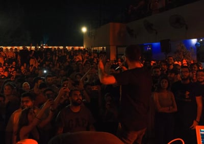 a man standing in front of a crowd of people performing rap music in lebanon