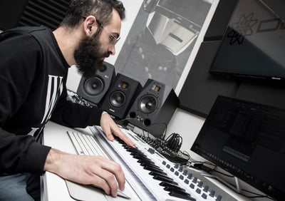 a man in a black shirt is playing a midi keyboard producing music in a studio lebanon