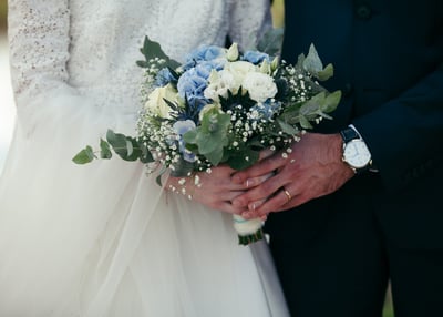 Des mariés en train de tenir le bouquet/a bride and groom holding a bouquet of flowers