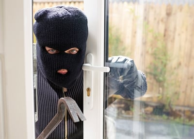 masked burgler breaking into home