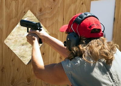 Female shooting 9mm handgun on range