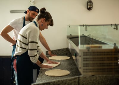 Femme qui apprend a faire des pizzas avec son professeur