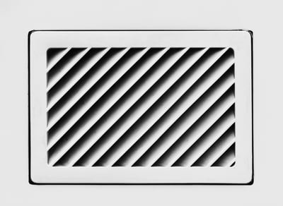 Angled black slats inside a white rectangular vent.