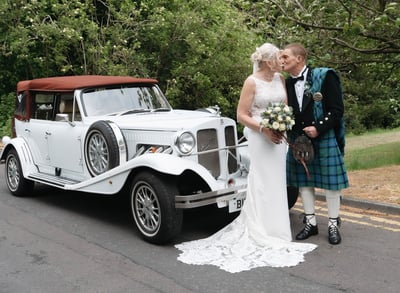 a bride and groom standing next to a car