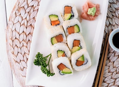 a plate of sushi rolls with chopsticks and sauce