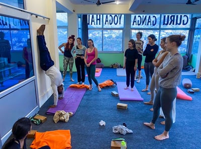 Yoga students practicing asanas together under the guidance of their teacher during a training session in Rishikesh, India.