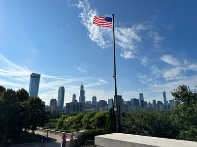 A United States flag with the Chicago city skyline in the background