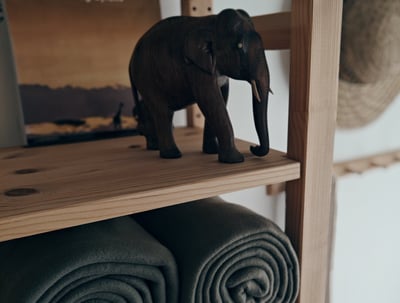 a toy elephant standing on a shelf with towels and towels