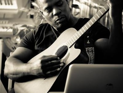 Dr. Marlon Ware sitting and playing a guitar