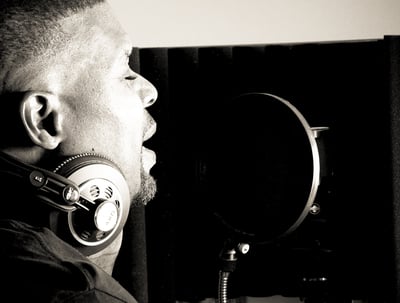 Dr. Marlon Ware standing in front of a microphone with headphones on his ears