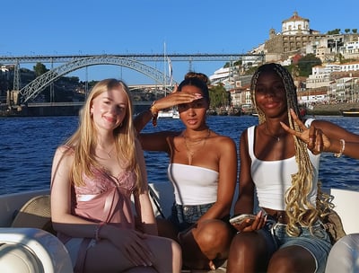 Three girls posing for a photo on the Endure speedboat with Dom Luís I Bridge in the background