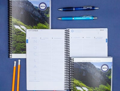 a notebook with a notepad and pens on a blue background