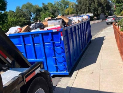 a dumpster truck with a large amount of trash in the back of it