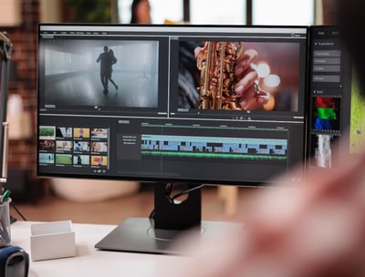 a man sitting at a desk with a computer monitor showing a video editing software