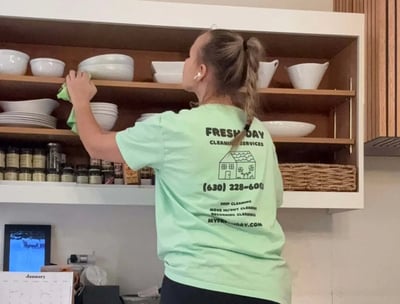 A professional cleaner thoroughly cleans a kitchen shelf with dishes