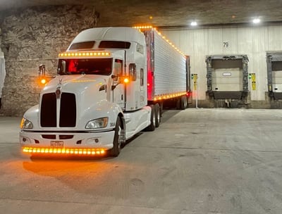 a semi truck with a trailer backed into a dock at an amazon facility